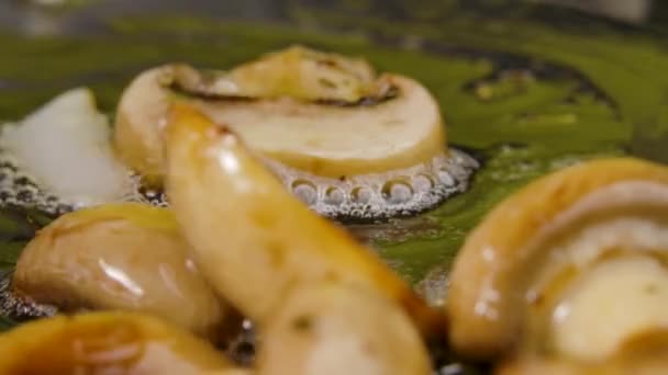 Διαδικασία μαγειρέματος τηγανιτών μανιταριών champignon με κρεμμύδι σε ελαιόλαδο σε τηγάνι, κοντινό πλάνο. Ανακατεύοντας τηγανητό κρεμμύδι και champignons με κόκκινη σπάτουλα. Μακρο-βολή. Αργή κίνηση. — Αρχείο Βίντεο