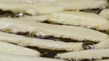 Kızarmış patates şeritlerini yağlı ve baharatlı sıcak bir tavaya koymak. Patates kızartması Patates parçaları kızgın yağda kızartılır. Restoran için güzel bir duvar kâğıdı. Yavaş çekim.