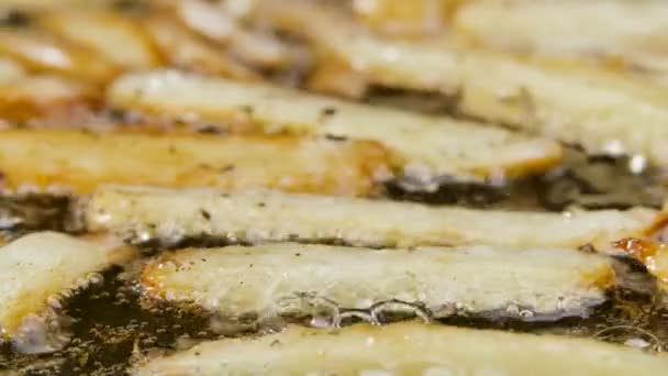 As fatias crocantes douradas de batatas são fritas em óleo em uma frigideira quente na cozinha. O processo de cozinhar um prato de batata de perto. Papel de parede bonito de cozinhar para restaurante. Movimento lento. — Vídeo de Stock