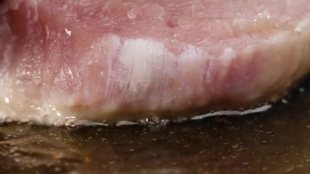 Schweinesteak fällt in einer heißen Pfanne in Butter. Nahaufnahme des Prozesses, ein Fleischgericht zu rösten. Abendessen kochen. Schöne Tapete des Kochens für Restaurant. Zeitlupe. — Stockvideo