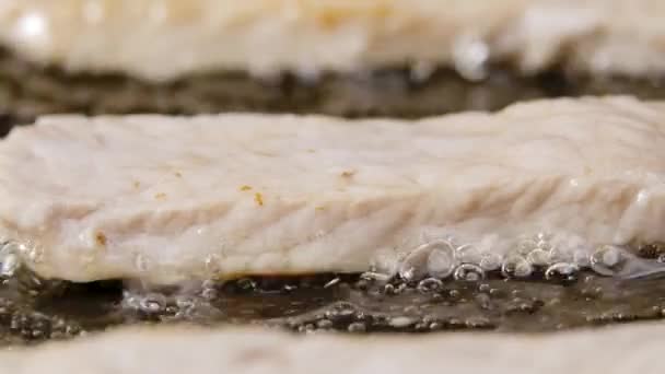 Las tiras de filete de pollo se fríen en aceite en una sartén caliente. Trozos jugosos de pavo están fritos. Primer plano de cocción plato de carne saludable jugosa. Hermoso fondo de pantalla de cocina para restaurante. Movimiento lento. — Vídeos de Stock