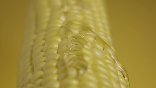 El goteo de miel o aceite espeso y viscoso fluye sobre los granos de maíz amarillo maduro. El néctar dulce envuelve la mazorca de oro del maíz fresco. Textura de semilla de maíz. De cerca. Cámara lenta lista, 4K a 59.94fps. — Vídeo de stock