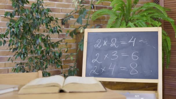 Tomma klassrum med skrivbord, skrivbord och lärobok. Skolor, hemundervisning, distansundervisning. Studerar aritmetik i grundskolan, första lektionen, skolkunskap. Interiör i modernt tomt klassrum — Stockvideo