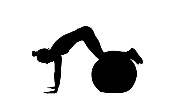 Die schwarze Silhouette einer jungen Frau dreht sich auf einem Fitnessball. Training für Arme, Rückenmuskulatur und Bauch, Fitness für Frauen. Seitenansicht in voller Länge auf weißem Hintergrund. Zeitlupe bereit 59.94fps. — Stockvideo
