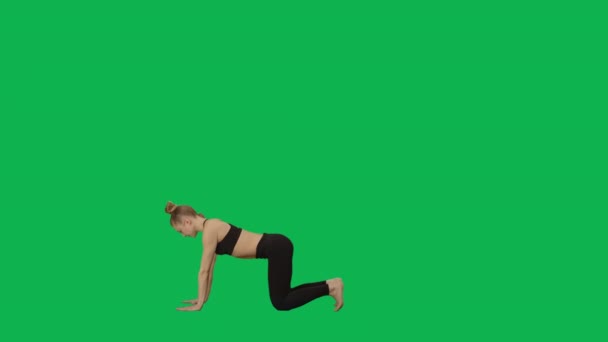Mujer joven en ropa deportiva haciendo yoga, estirando el cuerpo. Entrenamiento, fitness para mujeres, aeróbic. Vista lateral de longitud completa sobre fondo de pantalla verde. Cámara lenta lista 59.94fps. — Vídeo de stock