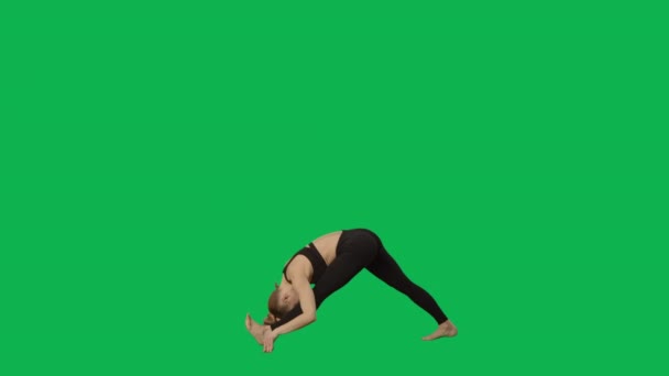 Junge Frau in Sportkleidung macht Yoga und dehnt den Körper. Workout, Fitness für Frauen, Aerobic. Seitenansicht in voller Länge auf grünem Hintergrund. Zeitlupe bereit 59.94fps. — Stockvideo