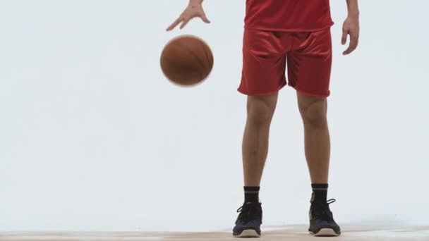 Silhouette of basketball player in sportswear dribbles ball practicing skills on white studio background. Professional player trains before basketball competition. Close up. Slow motion ready 59.94fps — Stock Video