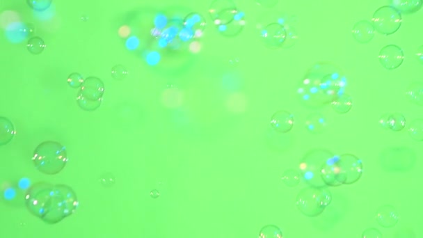 Сині і прозорі мильні бульбашки на зеленому фоні, повільний рух — стокове відео