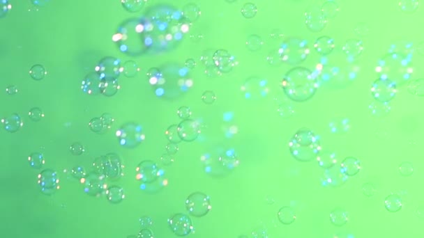Blaue und klare Seifenblasen auf hellgrünem Hintergrund, Zeitlupe — Stockvideo