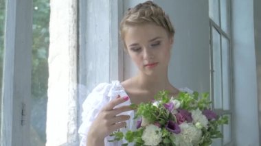 Vintage beyaz elbiseli güzel kız pencere üzerinde ond dokunaklı çiçekler, yavaş hareket oturan