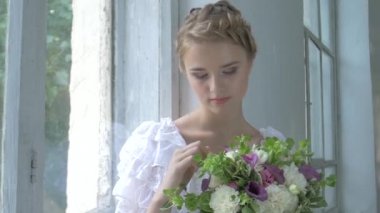 Vintage beyaz elbiseli güzel kız pencere üzerinde oturan ond dokunaklı çiçekler, gülümseyen, yavaş hareket