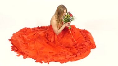 Gülümseyen, çiçekleri beyaz, yavaş hareket izole otururken, güzel Kırmızı elbiseli genç ve güzel kadın kokuyor