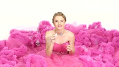 Güzel oturan güzel pembe elbiseli genç kız, darbe bubbles, gülümseyen, izole üzerinde beyaz, ağır çekim, kapatmak