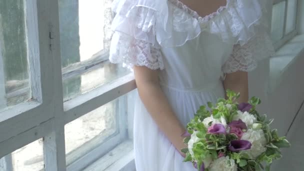 Menina bonita em vestido branco vintage sentado na janela ond assistindo jogar a janela, câmera lenta — Vídeo de Stock