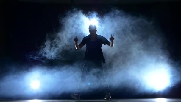 Um hip hop break-dançarino homem elegante em óculos de sol dança, fumaça, silhueta, câmera lenta — Vídeo de Stock