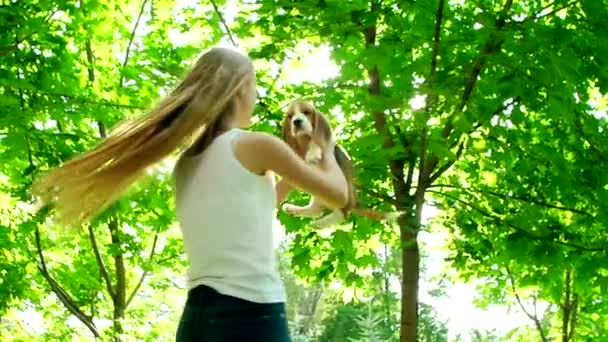 Girl with long hair playing with her beagle dog in park. Slow motion — Stock Video