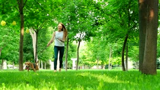 Feliz jovencita corriendo con su perro beagle. Movimiento lento — Vídeos de Stock