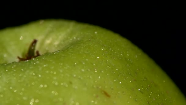Straně vlhké zelené jablko izolovaných na černou, rotace zblízka
