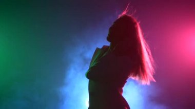 Güzel, büyüleyici, beyaz ceketli gülümseyen dj kız, kulağında kulaklık, oyun, müzik dinleme ve dans, duman, kamera bel, backlight, siluet kadar vuruyor