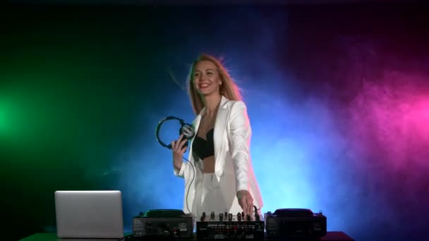 Linda, sorrindo dj menina em jaqueta branca, fones de ouvido tocando música e dança, fumaça — Vídeo de Stock