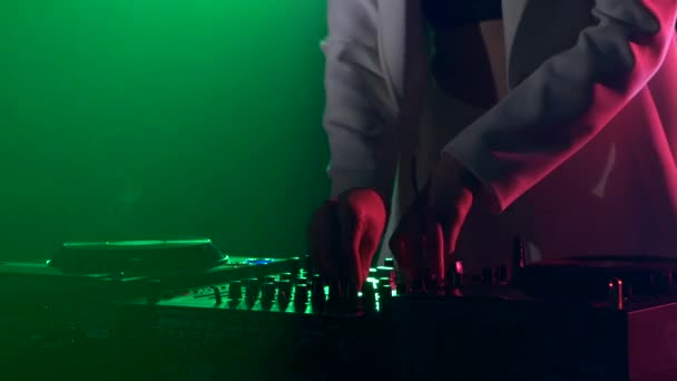 Beautiful, charming, smiling dj girl in white jacket, headphones on her ear, playing, listening music and dancing, smoke, green backlight, hand in her pocket — Stock Video