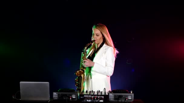 Young sexy, blonde woman dj playing music using saxophone on black — 图库视频影像