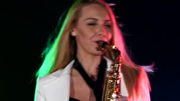 Jovem sexy, mulher loira dj em casaco branco tocando música usando saxofone em preto, close-up — Vídeo de Stock