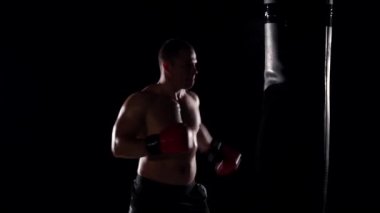 boks sırasında boksör adam eğitim fitness salonunda ağır çanta isabet. Yavaş çekim.