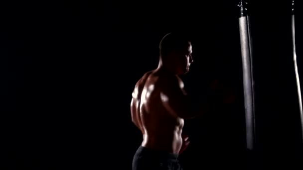 Boxeador hombre durante el boxeo golpeando bolsa pesada en el gimnasio de fitness de entrenamiento — Vídeos de Stock