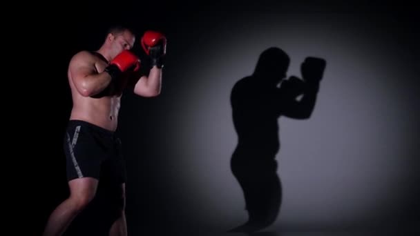 Boxeador entrenamiento sombra boxeo sobre fondo negro. Movimiento lento . — Vídeos de Stock