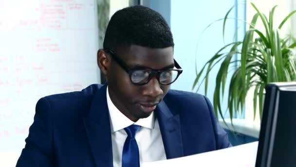 Afroamericano con gafas y un traje de negocios estudiando cuidadosamente las cartas . — Vídeos de Stock
