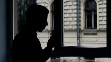 Pencerede duran işadamı, telefonda konuşurken önemli detayları tartışıyor. Siluet