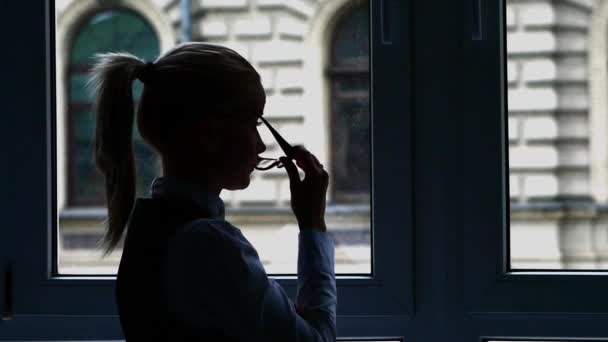 Silhouette affärskvinna stående vid fönstret efter en hektisk dag. Slow motion — Stockvideo