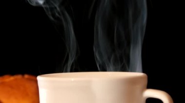 Siyah arka plan üzerinde kek ile beyaz buğulama kahve fincanı top
