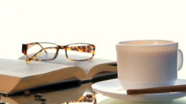 Lezzetli kahve ve kitap gözlük, tarçın, beyaz arka plan üzerinde fasulye ile