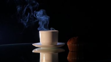 Siyah arka plan üzerinde kek ile beyaz fincan sıcak kahve
