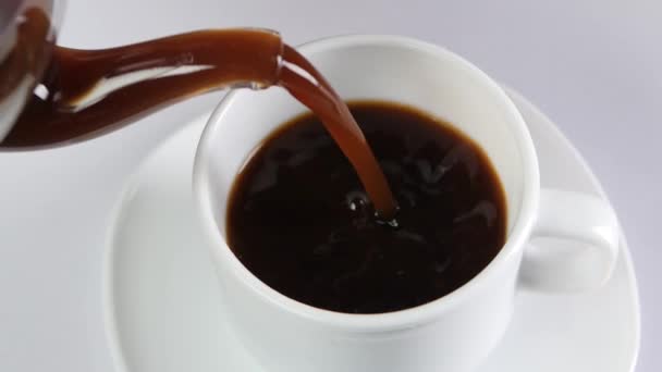Verser le café dans une tasse sur fond blanc, au ralenti 