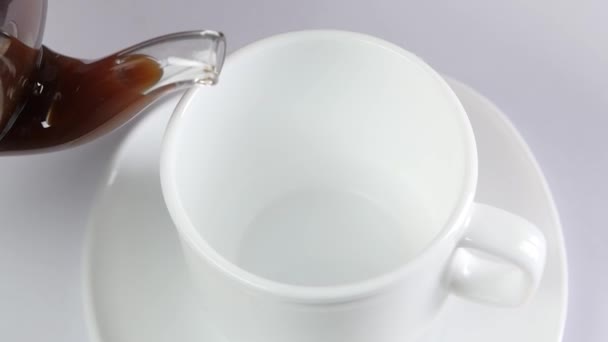 Café versé dans une tasse sur fond blanc, au ralenti 