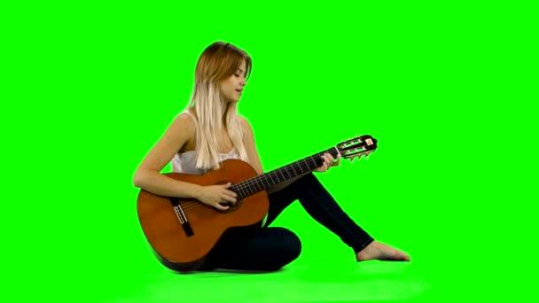 젊고 아름다운 코카서스 여성 이 원만 한 기타 연주를 하고 있습니다. 녹색 화면 — 비디오