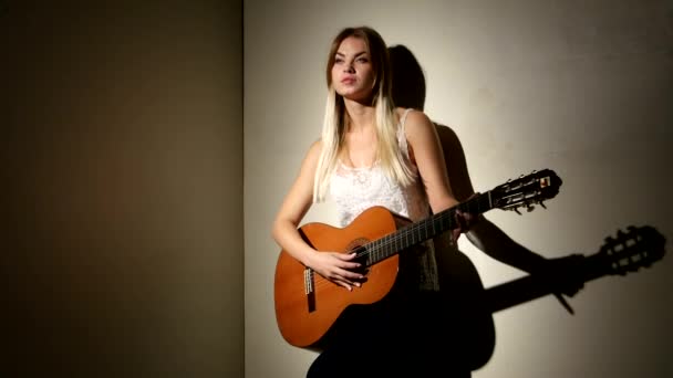 Linda chica toca en la guitarra acústica con emociones brillantes - aislado en el fondo negro . — Vídeo de stock