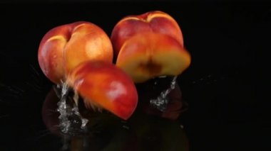 Şeftali su siyah bir arka plan ile masaya düşüyor. Yavaş çekim.