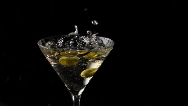 Två oliver som faller in i ett glas Martini. Slow motion — Stockvideo