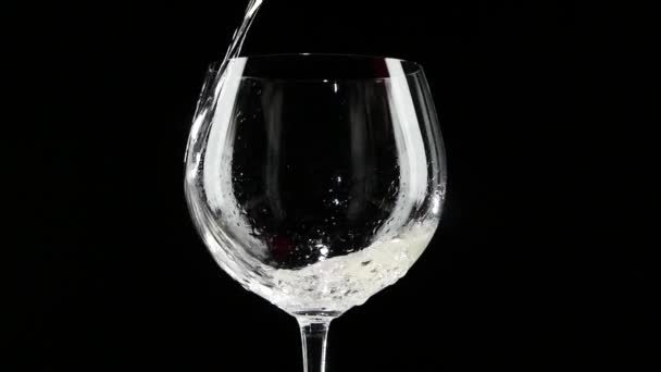 Weißwein wird in ein Glas mit schwarzem Hintergrund gegossen. Zeitlupe. — Stockvideo