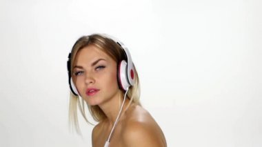 Beyaz arka plan üzerinde rüzgar saç üzerinde çırpınan ile müzik dinlerken kulaklık güzel kadın. Yavaş çekim.