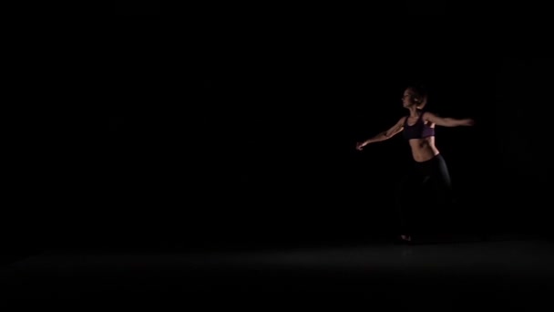 Young girl jumps dancing contemp in the shadow on black background, slow motion — Stok video