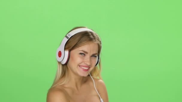 Joven hermosa chica rubia bailando con auriculares aislados en una pantalla verde — Vídeo de stock