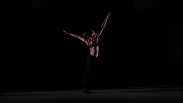 Танцовщица движется современно с необычными трюками в тени на черном фоне, замедленной съемки — стоковое видео
