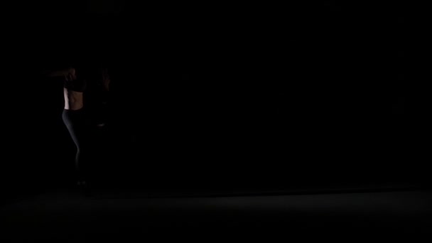 Beautiful girl dancing contemp in the shadow on black background, slow motion — Stock Video