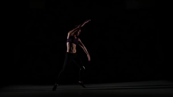 Young girl dancing contemp in the shadow on black background, slow motion — Stock video