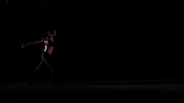 Atraktivní dívčí tanec uvažuje ve stínu na černém pozadí, pomalý pohyb — Stock video
